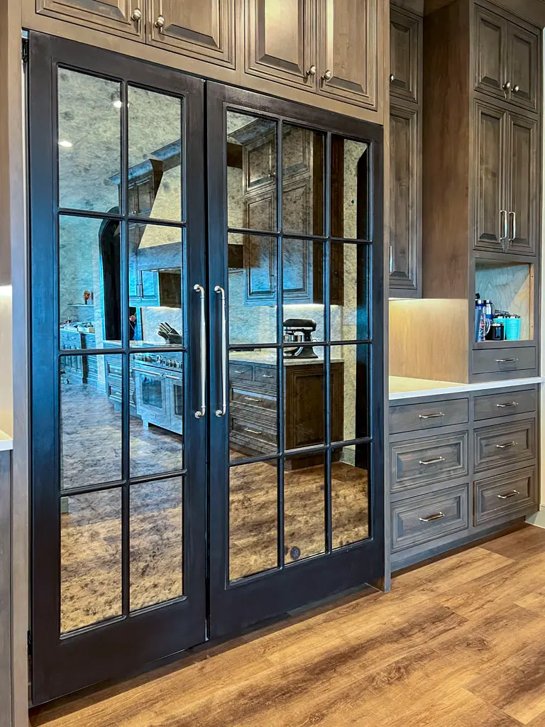 Custom dark-stained glass-panel pantry doors with wood cabinetry