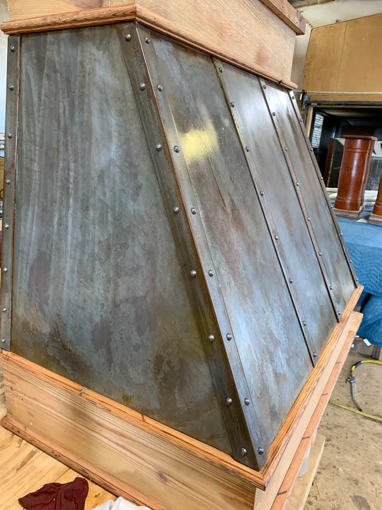 Hand-forged metal and wood range vent hood in workshop