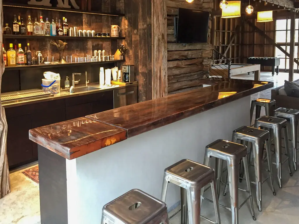 Custom reclaimed wood bar countertop with metal stools in rustic barn venue