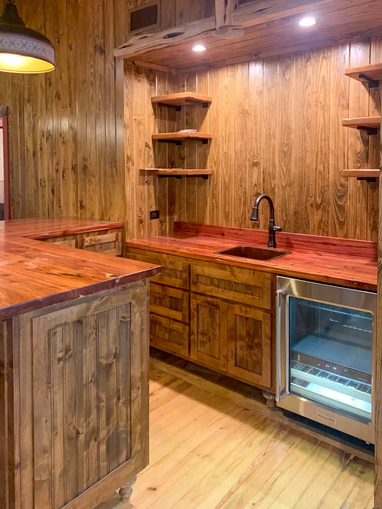Rustic wood wet bar with custom cabinetry and beverage cooler