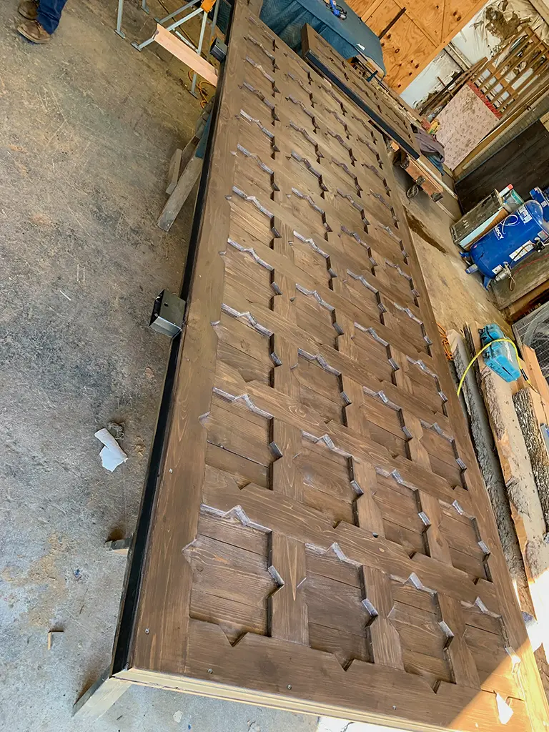 Custom stained wood gate with raised diamond-pattern panels built by Green Wood Milling Co in San Antonio, TX