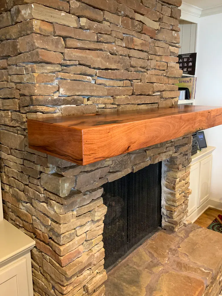 Wood mantle on stone fireplace surround by Green Wood Milling Co.