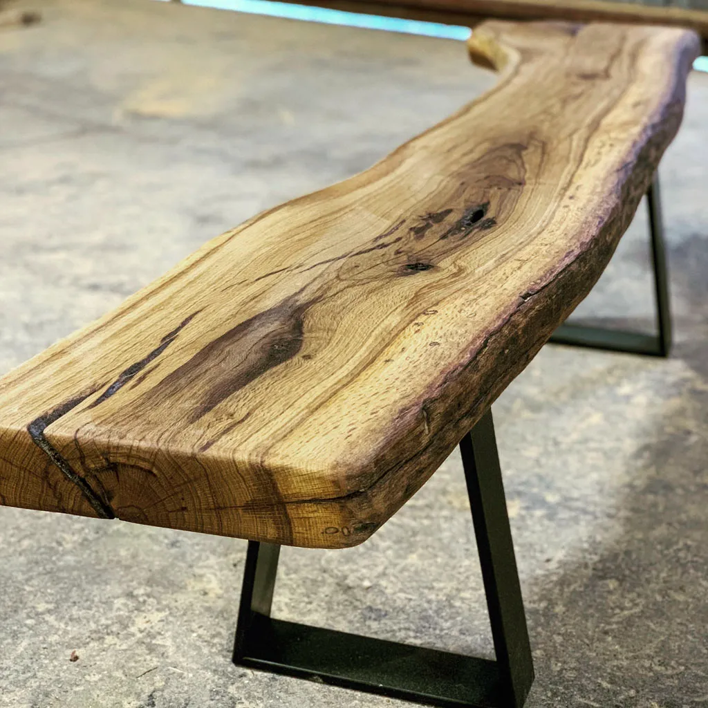 Live edge wooden bench with steel trapezoid legs for outdoor use