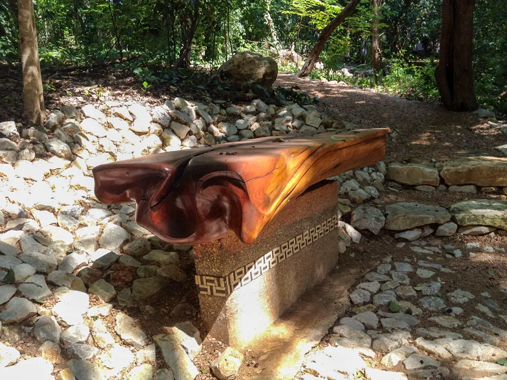 Sculpted live edge wood garden bench on stone pedestal