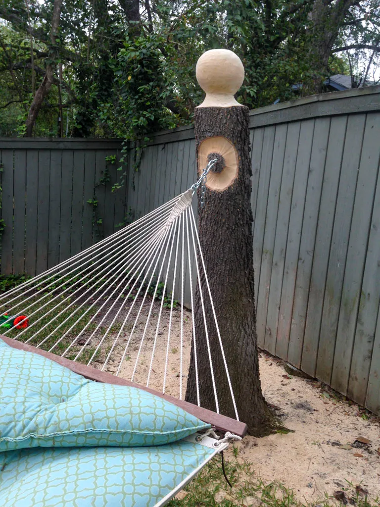 Carved wood hammock post with decorative ball finial in backyard