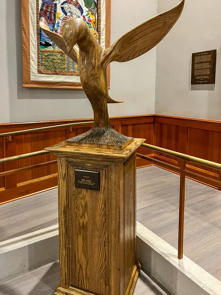 Hand-carved bird sculpture on wooden pedestal by Green Wood Milling Co.